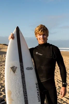 Blair Connor ancien rugbyman a coté de sa planche de surf